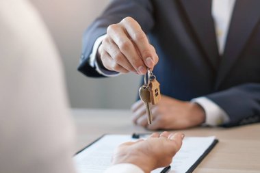 close up view hand of property realtor / landlord giving key house to buyer / tenant.
