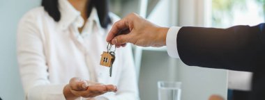 close up view hand of property realtor / landlord giving key house to buyer / tenant.