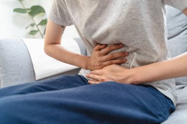 Young Asian woman suffering stomach pain from food poisoning.