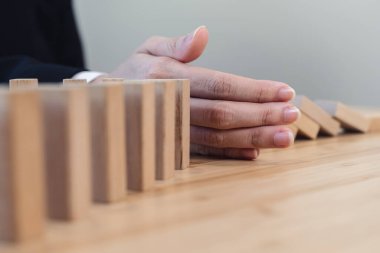 Protection finance from domino effect concept. Hands stop domino effect before destroy stack of money.