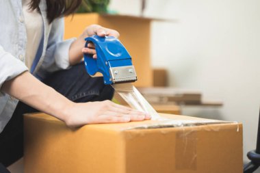 close up person sealing tape on parcel box prepare for delivery service to pick up.