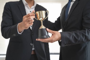 The hands of an employee receiving a golden cup reward from the company manager represent his performance in his career job reward.