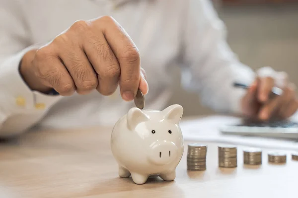 the person putting coin into piggy bank to save money and invest