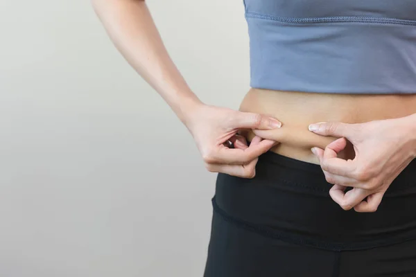 Close up Woman squeeze her belly and measuring fat on her waist
