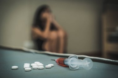close up pills and syringe on the bed.  Depressed woman suicide by using drug overdose.