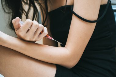 close up pills and syringe on the bed.  Depressed woman suicide by using drug overdose.