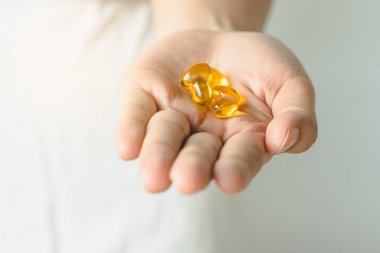 close-up view tablet of fish-oil supplement in woman hand.