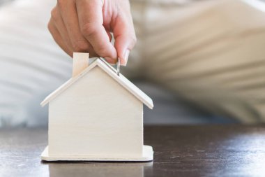 Hand of man saving money in piggy bank for future property.