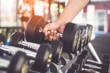 close-up of a man lifting dumbbells in the gym