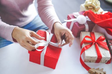 asian woman holding red gift box  on the hands offer to you on christmas tree background.