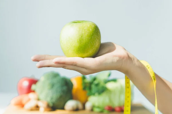 Healthy organic food for dieting woman concept. Woman carry green apple in front of healthy food and having a measure on her arm.