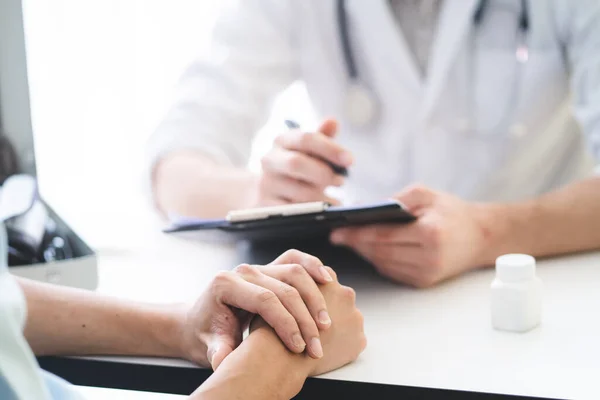 Doctor listening patient explain his symptom and notes to medical record.