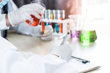 Group of college student doing chemical laboratory test during chemistry classroom. Student taking note of laboratory result.