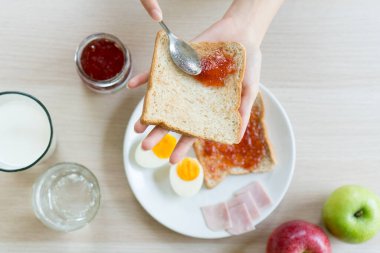 Person having breakfast on the table eat apple, egg, jam and milk the menu for dieting. plan.