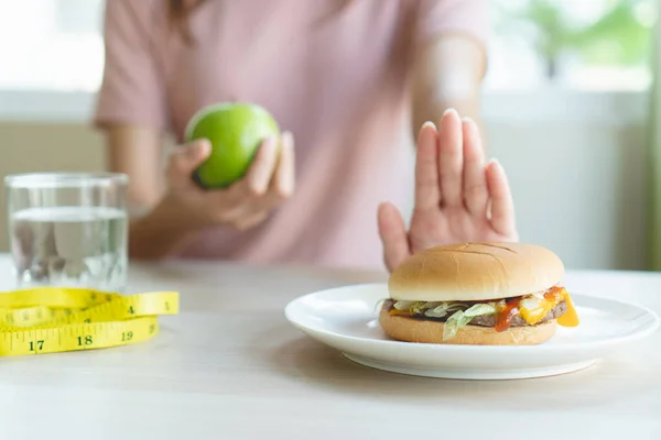 Woman on dieting for good health concept. Woman doing cross arms sign to refuse junk food or fast food (hamburger and potato fried) that have many fat.