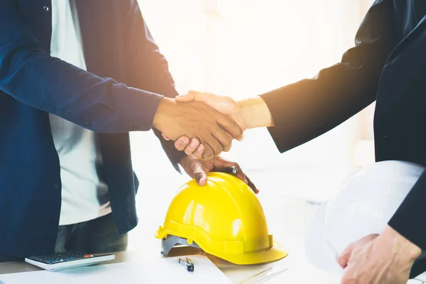 Successful deal, male architect shaking hands with client in construction site after confirm blueprint for renovate building.