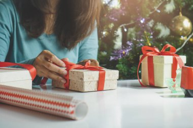 creative ideas handmade gift for holidays. boxes woman tying red bow decorated the craft presents box prepare for christmas night party.