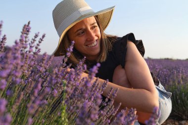 beautiful smiling woman gazing at the lavender fields at sunset