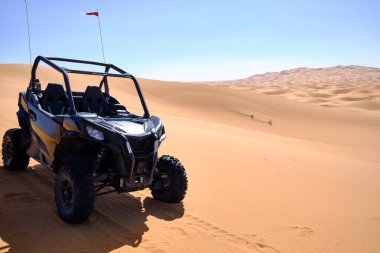 Kuzey Afrika 'daki Fas' ın Merzouga çölünde kumulsuz mavi gökyüzüne park etmiş iki koltuklu ATV.