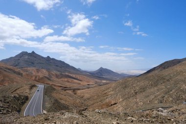 Fuerteventura adasının iç kısımlarında kurak dağlarla çevrili bir yol.