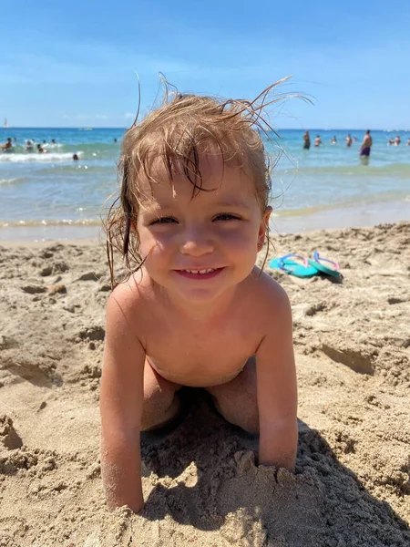 stock image Valencia, Spain, August 19, 2022: Smiling girl looking at the camera, with her hands in the sand on the beach.