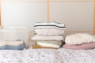 Kazaklı bir kutunun yanında kış süveteri yığını. Mevsimlerin değişimi kavramı