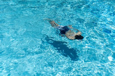 Mavi suyun altına dalan tanınmayan bir çocuğun odaksız silueti.