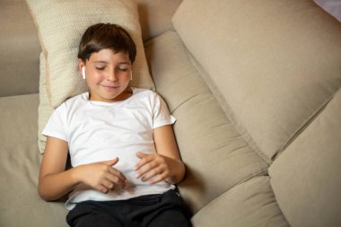 Müzik ve rahatlama: çocuk kanepede rahatlar ve en sevdiği şarkıları dinler.