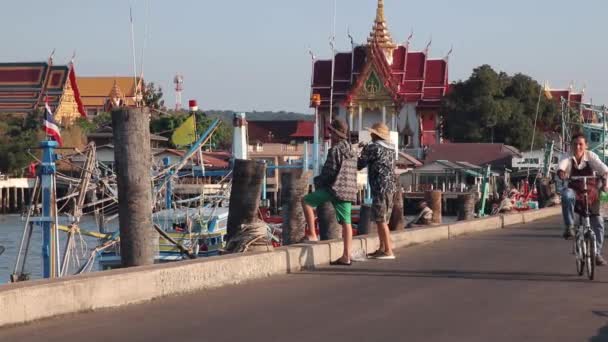 釣りの桟橋には釣り人や自転車 背景には仏教寺院 — ストック動画