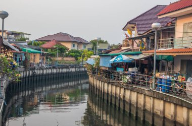 Tayland ve Asya 'da balıkçı tekneleri, binaları ve ev cepheleri olan klong veya nehir kanalı