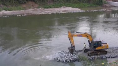 Kazı araçları ya da makineler, Luang Prabang, Laos, Asya 'daki Mekong Nehri' ne akan Nam Khan Nehri boyunca toprak ıslahı için moloz, çakıl ve daha büyük sert kayalar taşır.