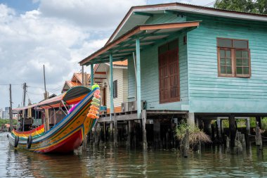 Chao Phraya nehrinin uzun kuyruklu ahşap botları ve Bangkok Tayland Asya 'daki konut binaları olan klong veya nehir kanalı.