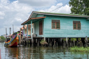Chao Phraya nehrinin uzun kuyruklu ahşap botları ve Bangkok Tayland Asya 'daki konut binaları olan klong veya nehir kanalı.
