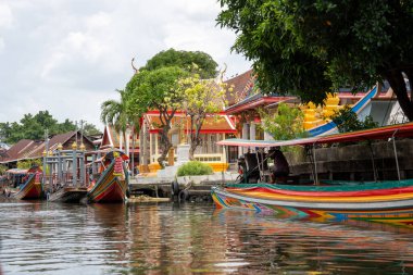Chao Phraya nehrinin uzun kuyruklu ahşap botları ve Bangkok Tayland Asya 'daki konut binaları olan klong veya nehir kanalı.