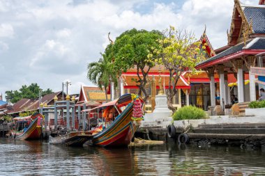 Chao Phraya nehrinin uzun kuyruklu ahşap botları ve Bangkok Tayland Asya 'daki konut binaları olan klong veya nehir kanalı.