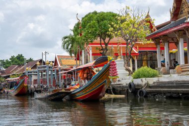 Chao Phraya nehrinin uzun kuyruklu ahşap botları ve Bangkok Tayland Asya 'daki konut binaları olan klong veya nehir kanalı.