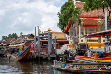 Chao Phraya nehrinin uzun kuyruklu ahşap botları ve Bangkok Tayland Asya 'daki konut binaları olan klong veya nehir kanalı.