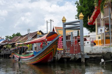 Chao Phraya nehrinin uzun kuyruklu ahşap botları ve Bangkok Tayland Asya 'daki konut binaları olan klong veya nehir kanalı.