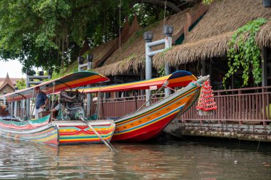 Chao Phraya nehrinin uzun kuyruklu ahşap botları ve Bangkok Tayland Asya 'daki konut binaları olan klong veya nehir kanalı.