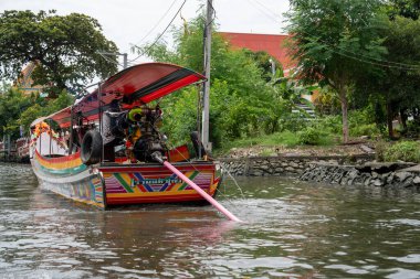 Chao Phraya nehrinin uzun kuyruklu ahşap botları ve Bangkok Tayland Asya 'daki konut binaları olan klong veya nehir kanalı.