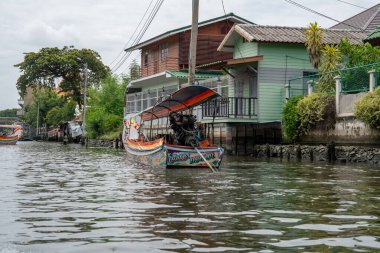 Chao Phraya nehrinin uzun kuyruklu ahşap botları ve Bangkok Tayland Asya 'daki konut binaları olan klong veya nehir kanalı.