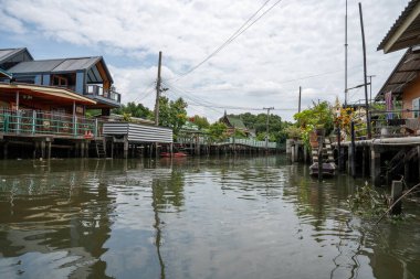 Chao Phraya nehrinin uzun kuyruklu ahşap botları ve Bangkok Tayland Asya 'daki konut binaları olan klong veya nehir kanalı.
