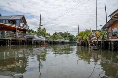 Chao Phraya nehrinin uzun kuyruklu ahşap botları ve Bangkok Tayland Asya 'daki konut binaları olan klong veya nehir kanalı.