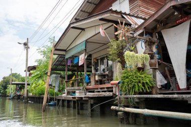 Chao Phraya nehrinin uzun kuyruklu ahşap botları ve Bangkok Tayland Asya 'daki konut binaları olan klong veya nehir kanalı.