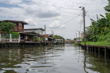 Chao Phraya nehrinin uzun kuyruklu ahşap botları ve Bangkok Tayland Asya 'daki konut binaları olan klong veya nehir kanalı.