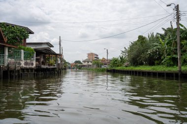 Chao Phraya nehrinin uzun kuyruklu ahşap botları ve Bangkok Tayland Asya 'daki konut binaları olan klong veya nehir kanalı.