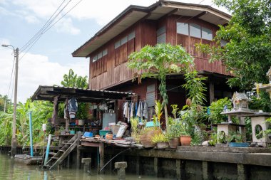 Chao Phraya nehrinin uzun kuyruklu ahşap botları ve Bangkok Tayland Asya 'daki konut binaları olan klong veya nehir kanalı.