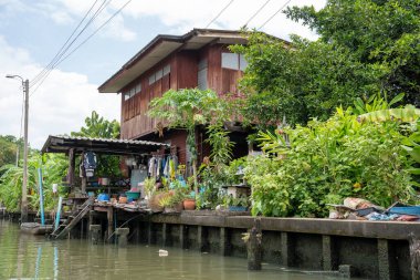 Chao Phraya nehrinin uzun kuyruklu ahşap botları ve Bangkok Tayland Asya 'daki konut binaları olan klong veya nehir kanalı.