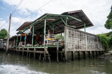 Chao Phraya nehrinin uzun kuyruklu ahşap botları ve Bangkok Tayland Asya 'daki konut binaları olan klong veya nehir kanalı.