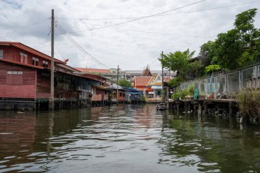 Chao Phraya nehrinin uzun kuyruklu ahşap botları ve Bangkok Tayland Asya 'daki konut binaları olan klong veya nehir kanalı.